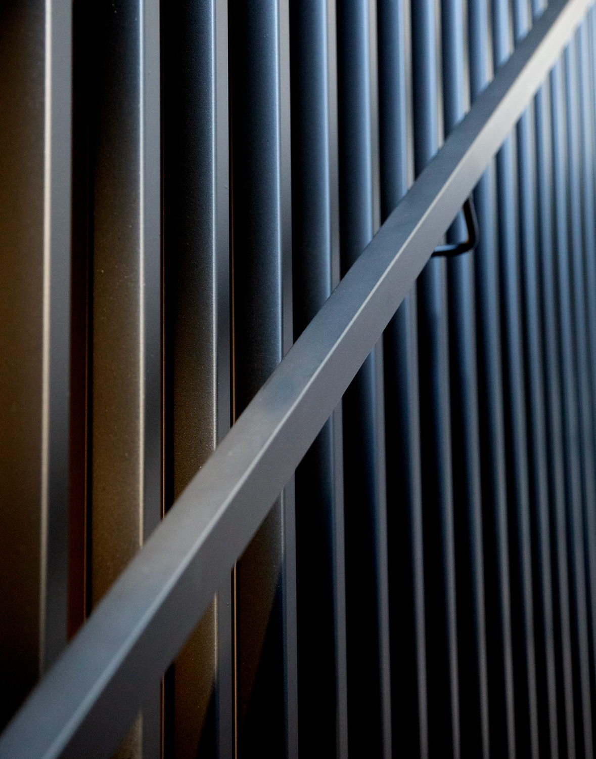 Close-up view of custom vertical iron balusters surrounding a staircase, creating an interplay of light and shadow in a modern Phoenix home.