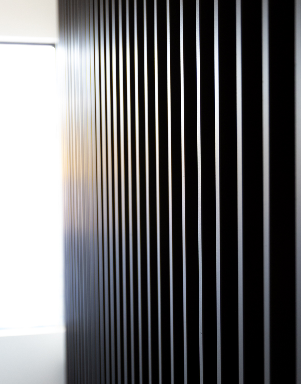 Upward view of sleek black ironwork lit by sunlight, emphasizing modern geometry and architectural rhythm.